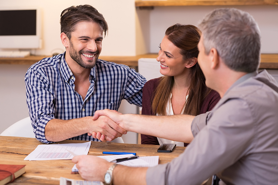 Smiling couple shaking hands with loan officer