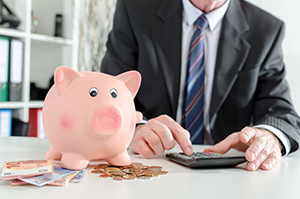 Photo of Business Man Using Calculator with Piggy Bank in View