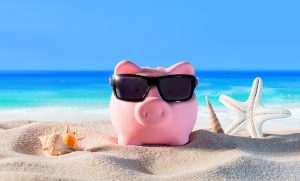 Piggy bank wearing sunglasses on a sandy beach