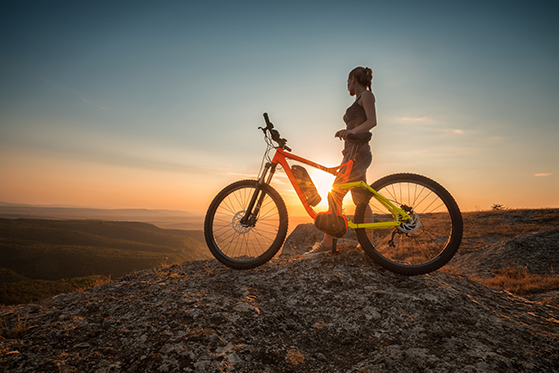 Woman with electric bike viewing sunset in the desert