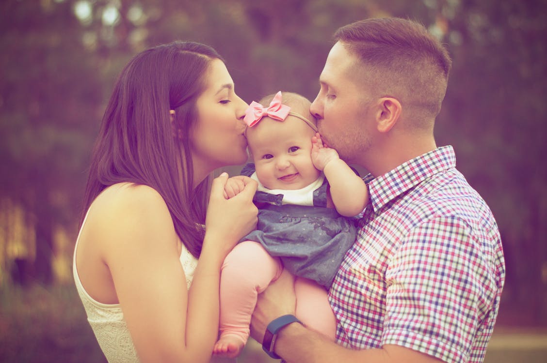 Photo of young couple kissing baby